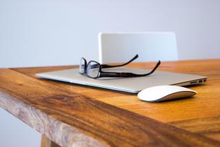 glasses atop a computer atop a wooden table