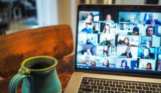 A laptop with a video conference call displayed on the screen