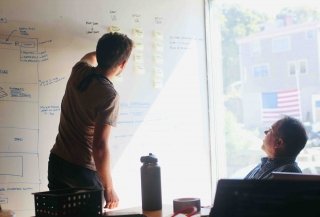 Two colleagues review website redesign scoping requirements on a white board