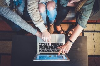 A group of prospective students research colleges together on a laptop