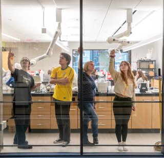 Seattle University students writing on a glass window with wax pencils